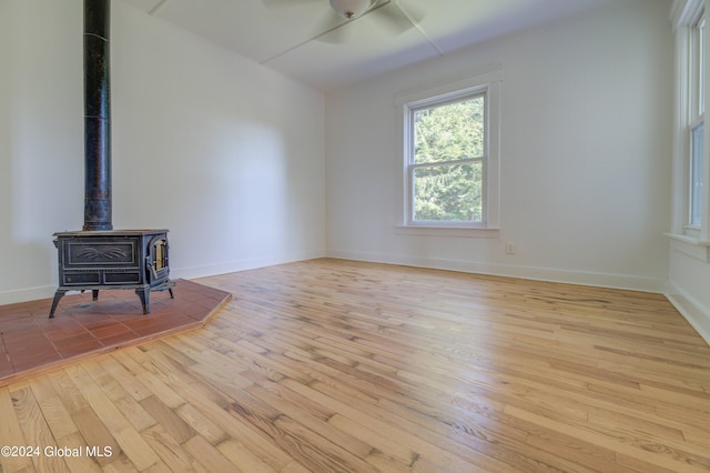 spare room featuring a wood stove, ceiling fan, and light hardwood / wood-style floors