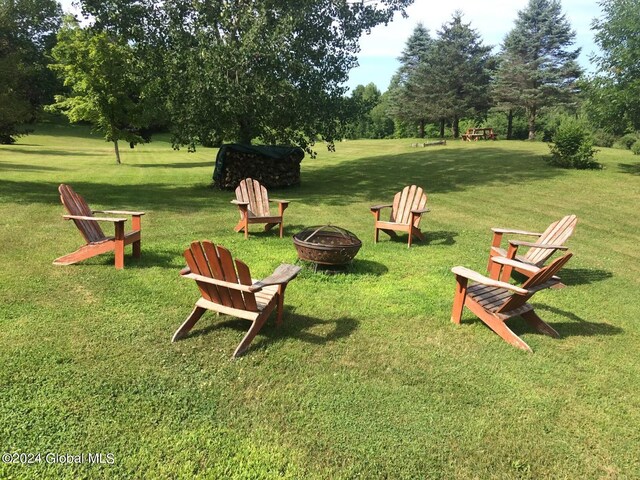 view of property's community with an outdoor fire pit and a yard