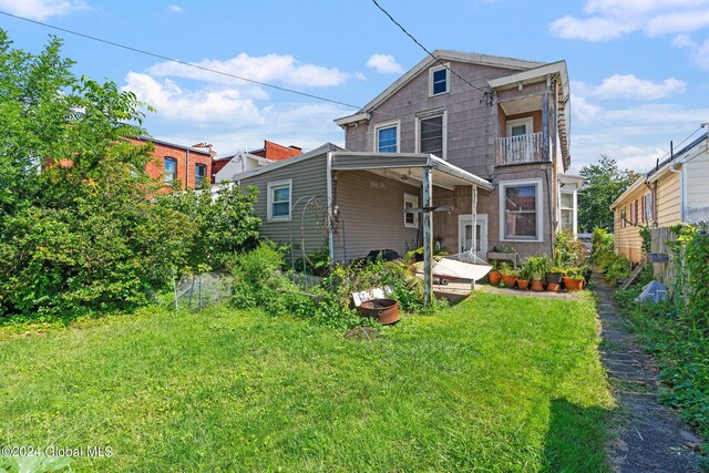 back of house featuring a balcony and a yard