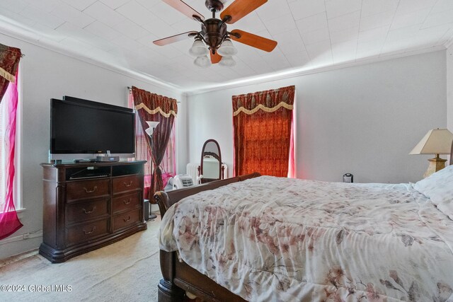 carpeted bedroom featuring crown molding and ceiling fan