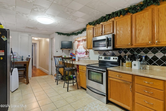 kitchen featuring appliances with stainless steel finishes, light tile patterned floors, and tasteful backsplash