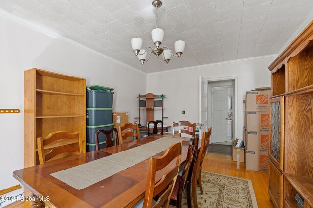 dining space featuring light wood-type flooring, a notable chandelier, and crown molding