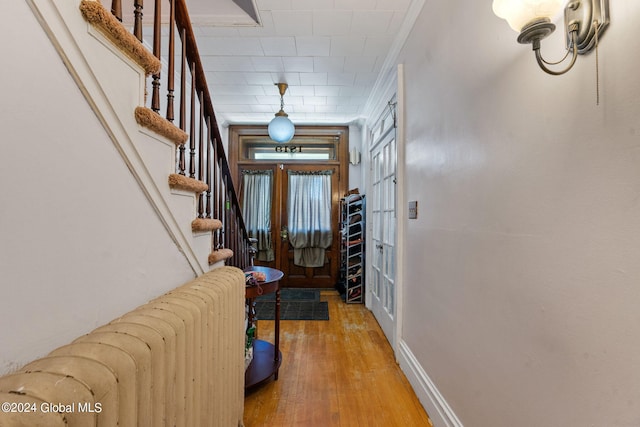 foyer with wood-type flooring, radiator, and ornamental molding