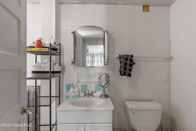 bathroom featuring vanity, toilet, and tile walls