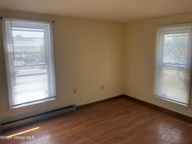 spare room with baseboards, baseboard heating, and wood finished floors