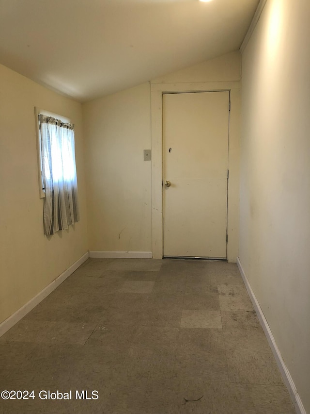 empty room with vaulted ceiling and baseboards