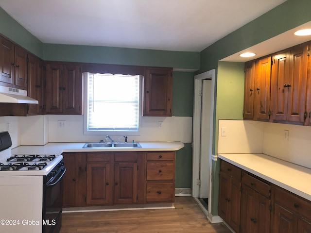 kitchen featuring gas range, under cabinet range hood, light countertops, and a sink