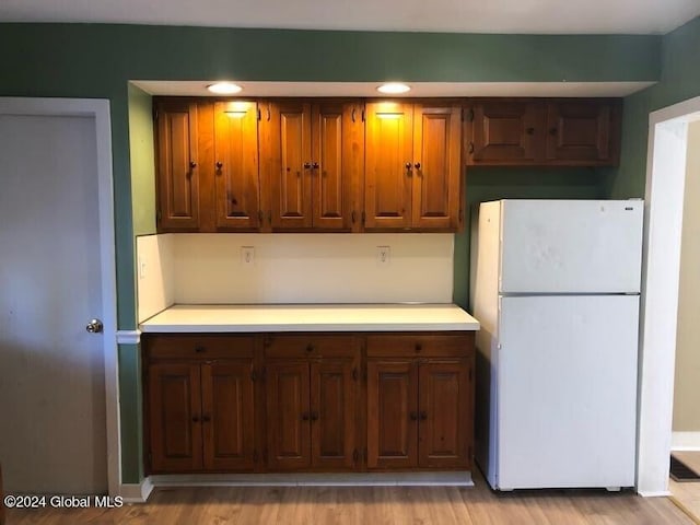 kitchen with light countertops, freestanding refrigerator, and light wood-style floors