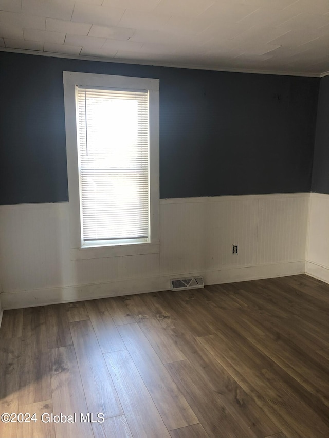 unfurnished room with a wainscoted wall, visible vents, and wood finished floors