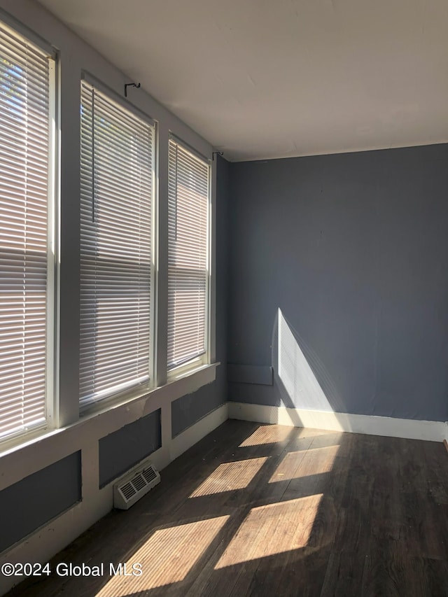 spare room featuring baseboards, visible vents, and wood finished floors