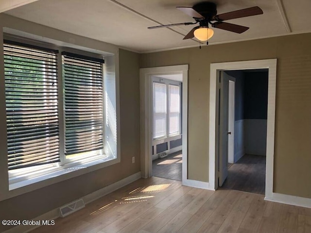 unfurnished room featuring a ceiling fan, baseboards, visible vents, and wood finished floors