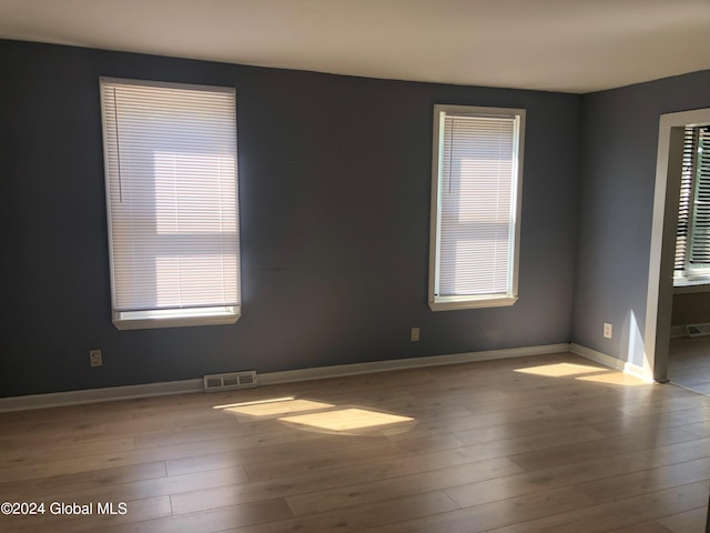 spare room with wood finished floors, visible vents, and baseboards