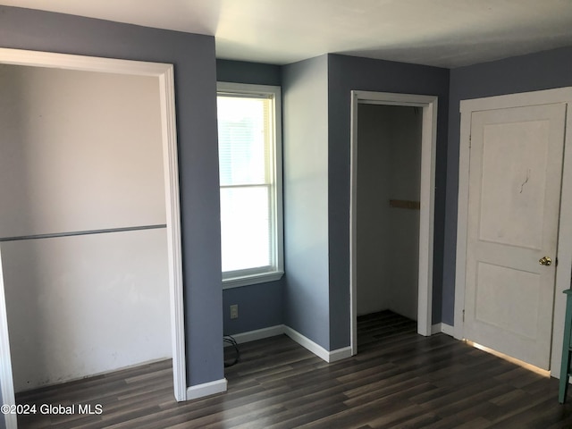 unfurnished bedroom featuring dark wood-type flooring, a closet, and baseboards