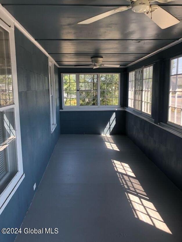 unfurnished sunroom featuring ceiling fan