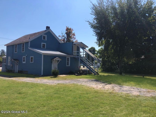 rear view of house featuring a lawn and stairs