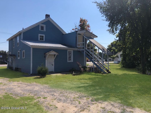 rear view of house with metal roof, a yard, stairway, and a chimney