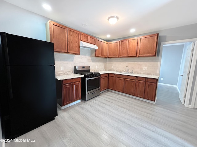 kitchen featuring gas range, sink, black fridge, decorative backsplash, and light wood-type flooring