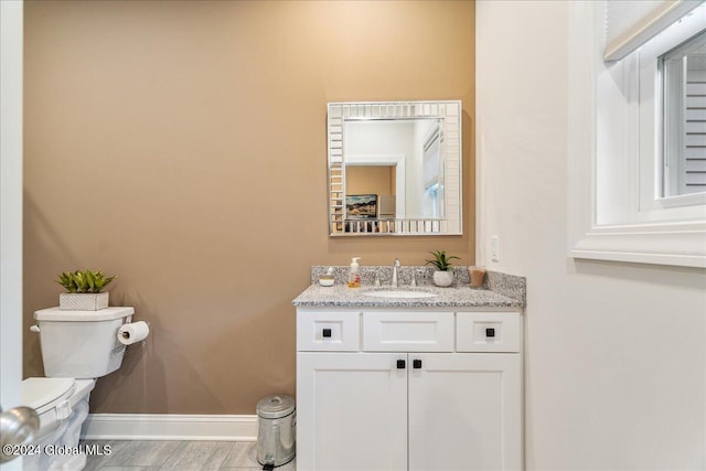 bathroom with hardwood / wood-style floors, vanity, and toilet