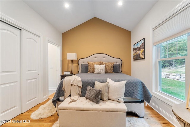 bedroom with light hardwood / wood-style floors, a closet, and lofted ceiling