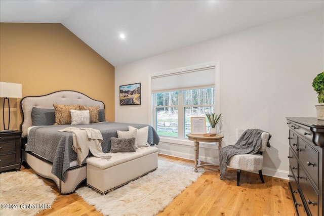 bedroom with light hardwood / wood-style floors and lofted ceiling