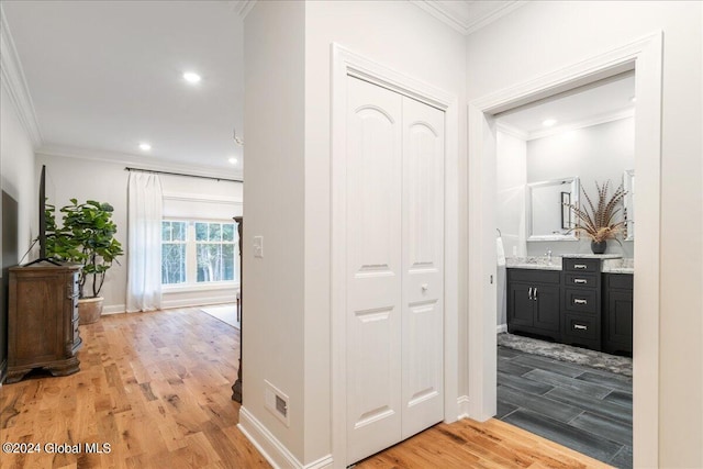 hallway with light hardwood / wood-style floors, ornamental molding, and sink