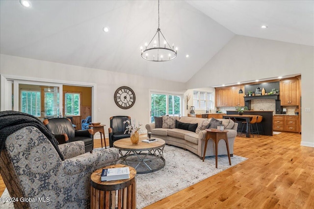 living room with a chandelier, high vaulted ceiling, and light hardwood / wood-style floors