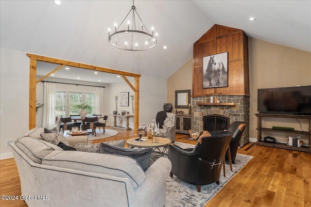 living room with a fireplace, light wood-type flooring, a chandelier, and high vaulted ceiling