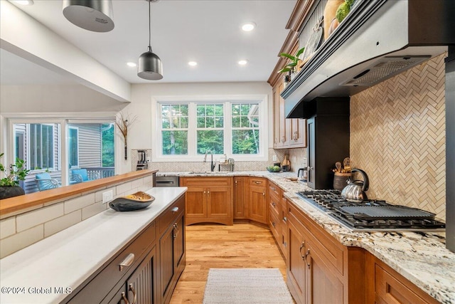 kitchen featuring pendant lighting, backsplash, sink, light hardwood / wood-style flooring, and custom range hood