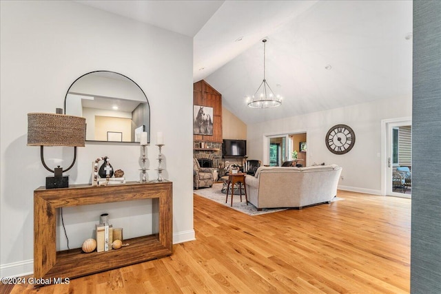 living room with light wood-type flooring, high vaulted ceiling, and a chandelier