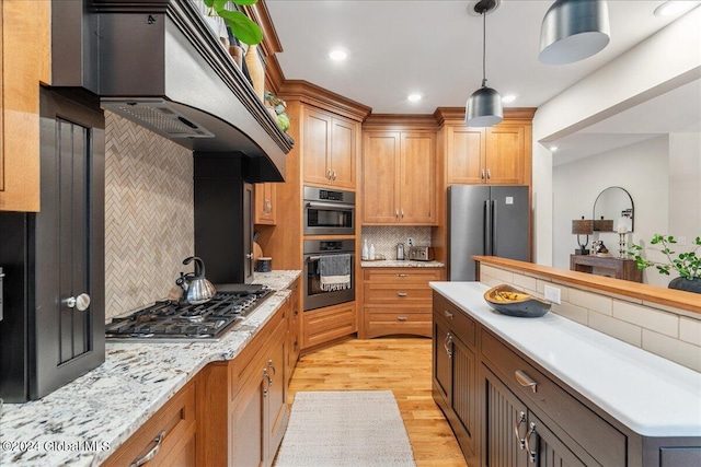 kitchen with backsplash, premium range hood, light hardwood / wood-style floors, decorative light fixtures, and appliances with stainless steel finishes