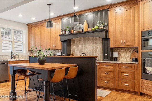 kitchen with a kitchen breakfast bar, light stone counters, pendant lighting, light hardwood / wood-style flooring, and dishwasher