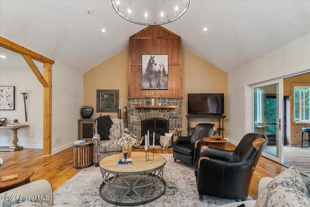 living room featuring a chandelier, high vaulted ceiling, light hardwood / wood-style flooring, and a stone fireplace