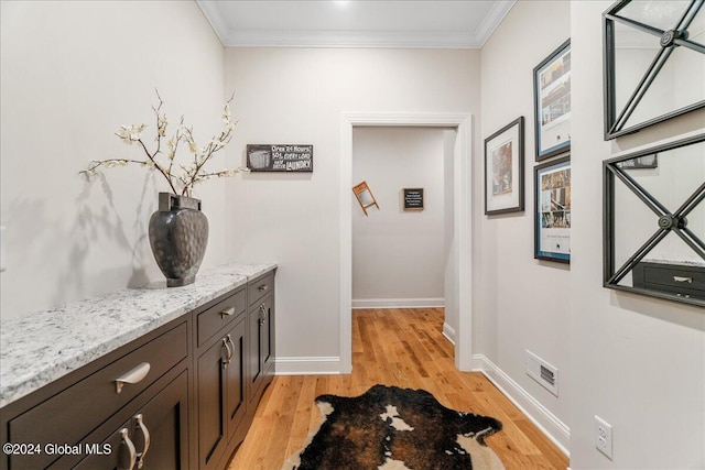 corridor with light hardwood / wood-style flooring and crown molding