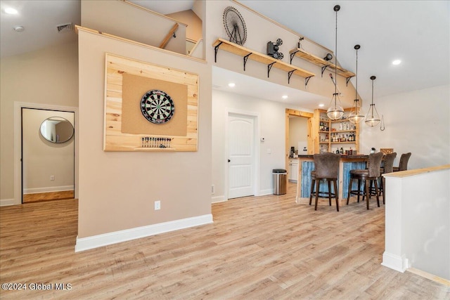 interior space with bar, high vaulted ceiling, and light wood-type flooring