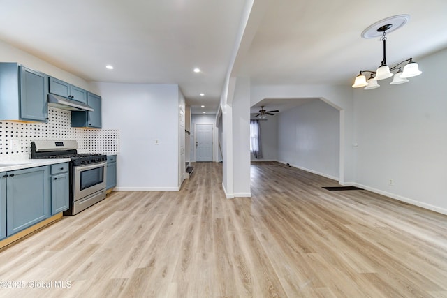 kitchen featuring pendant lighting, ceiling fan, light wood-type flooring, blue cabinetry, and stainless steel range with gas stovetop