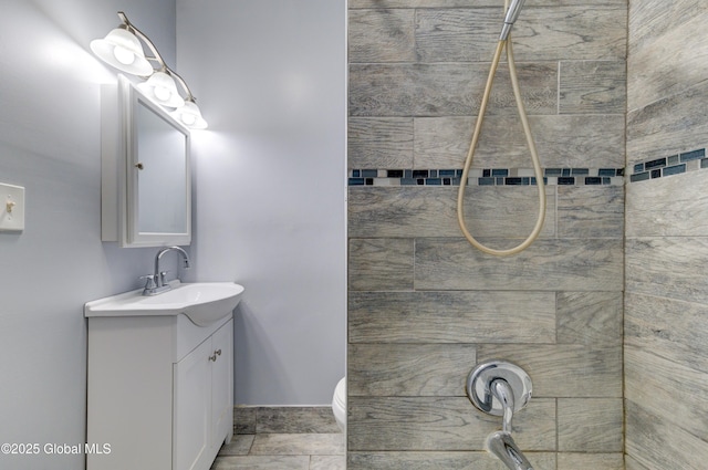 bathroom with a tile shower and vanity