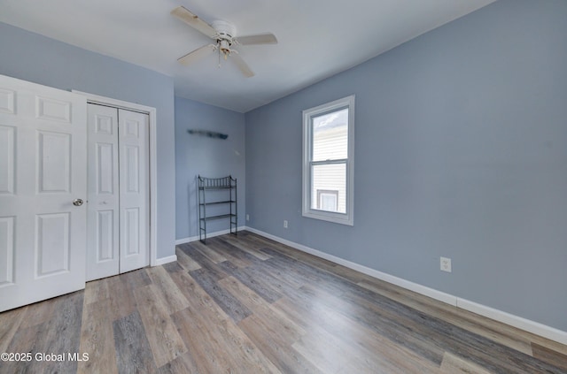 unfurnished bedroom with hardwood / wood-style flooring, ceiling fan, and a closet