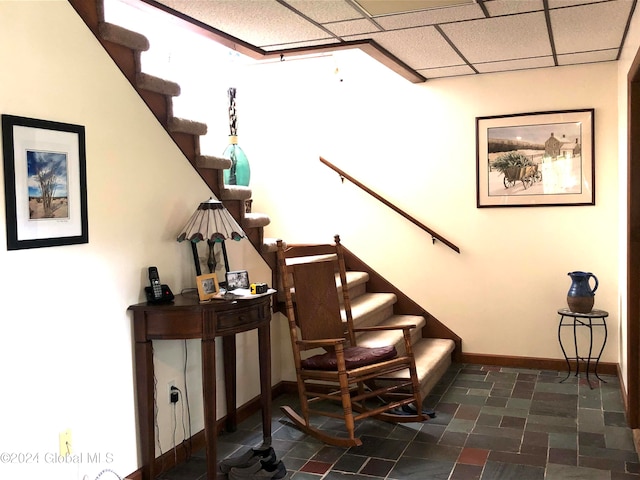 stairs with a paneled ceiling