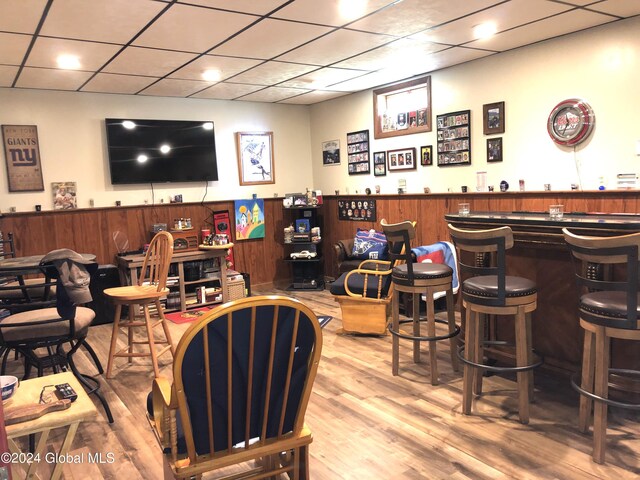 bar with a drop ceiling and hardwood / wood-style floors