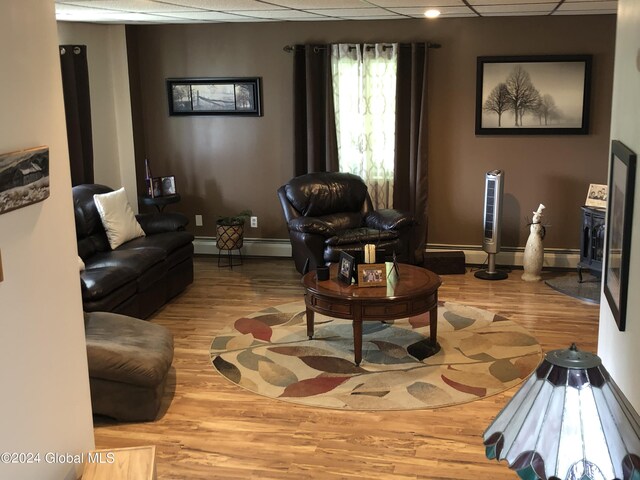 living room with a baseboard heating unit and wood-type flooring