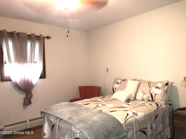 bedroom featuring a baseboard radiator, dark hardwood / wood-style floors, and ceiling fan