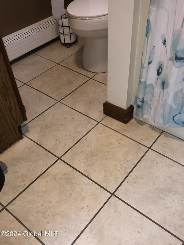 bathroom with tile patterned floors, a baseboard heating unit, and toilet