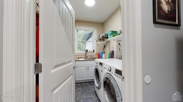 laundry area featuring washing machine and clothes dryer, cabinets, and sink