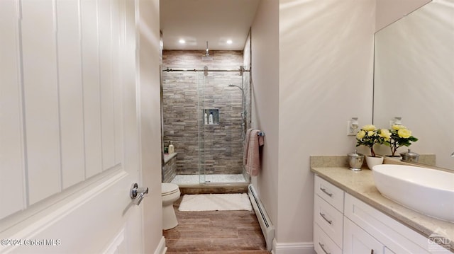 bathroom featuring a shower with door, a baseboard heating unit, toilet, wood-type flooring, and vanity