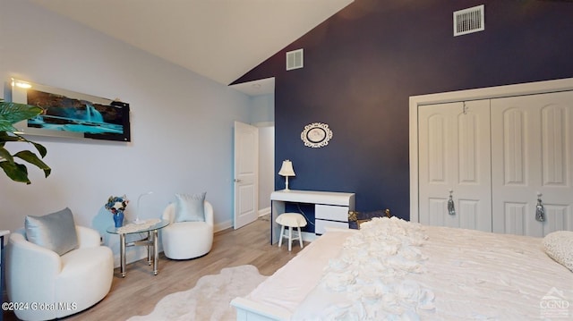 bedroom featuring high vaulted ceiling, hardwood / wood-style flooring, and a closet