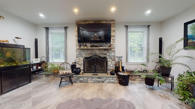 living room featuring a wealth of natural light and a stone fireplace