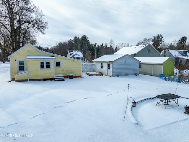 snow covered rear of property with an outdoor structure