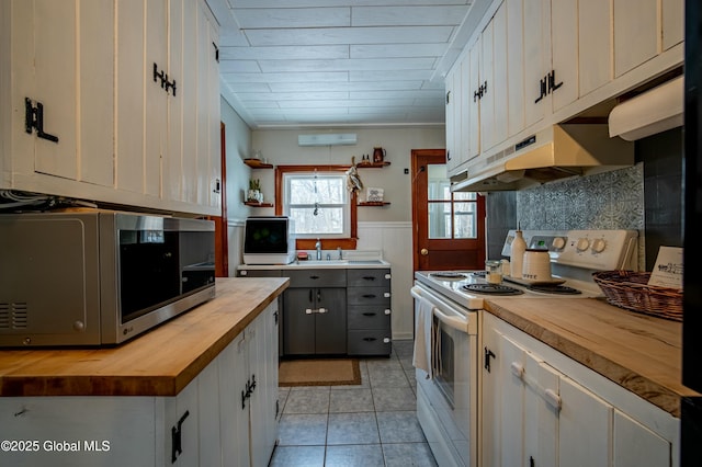 kitchen with light tile patterned flooring, wood counters, sink, white cabinetry, and electric stove