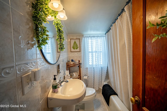 full bathroom with shower / bath combo, sink, tile walls, and toilet