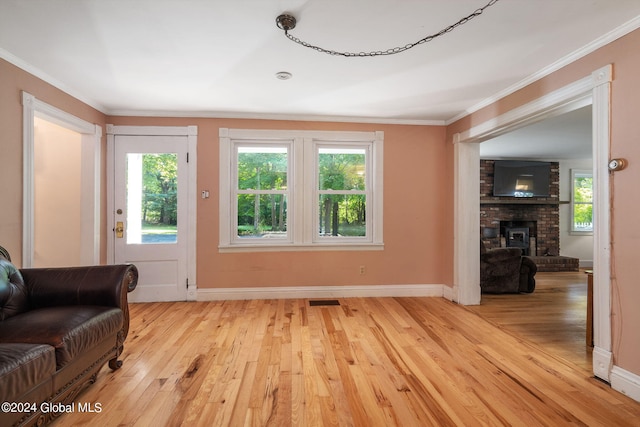 living area with a fireplace, light wood-type flooring, and ornamental molding